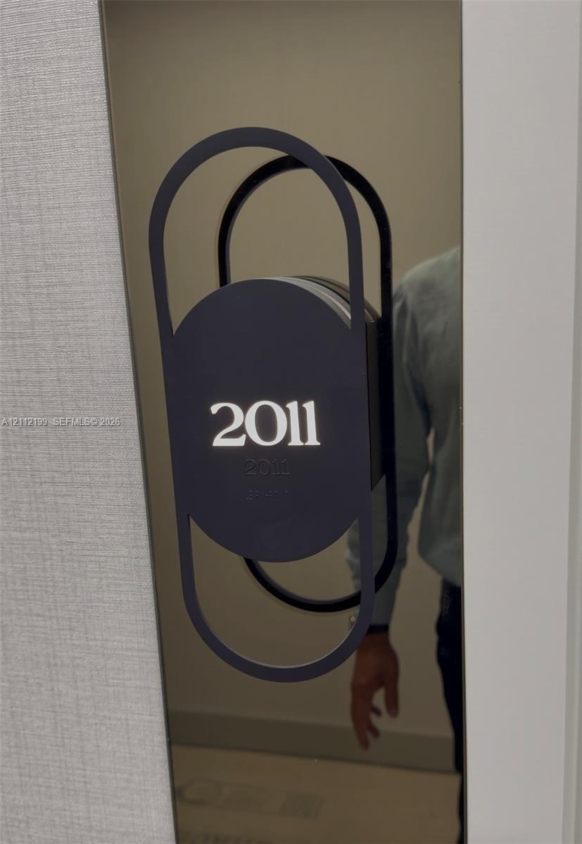 Modern metallic door plaque featuring a matte black geometric frame and integrated Braille signage