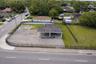 Expansive corner lot featuring a paved surface, structural covered area, and perimeter black metal fencing