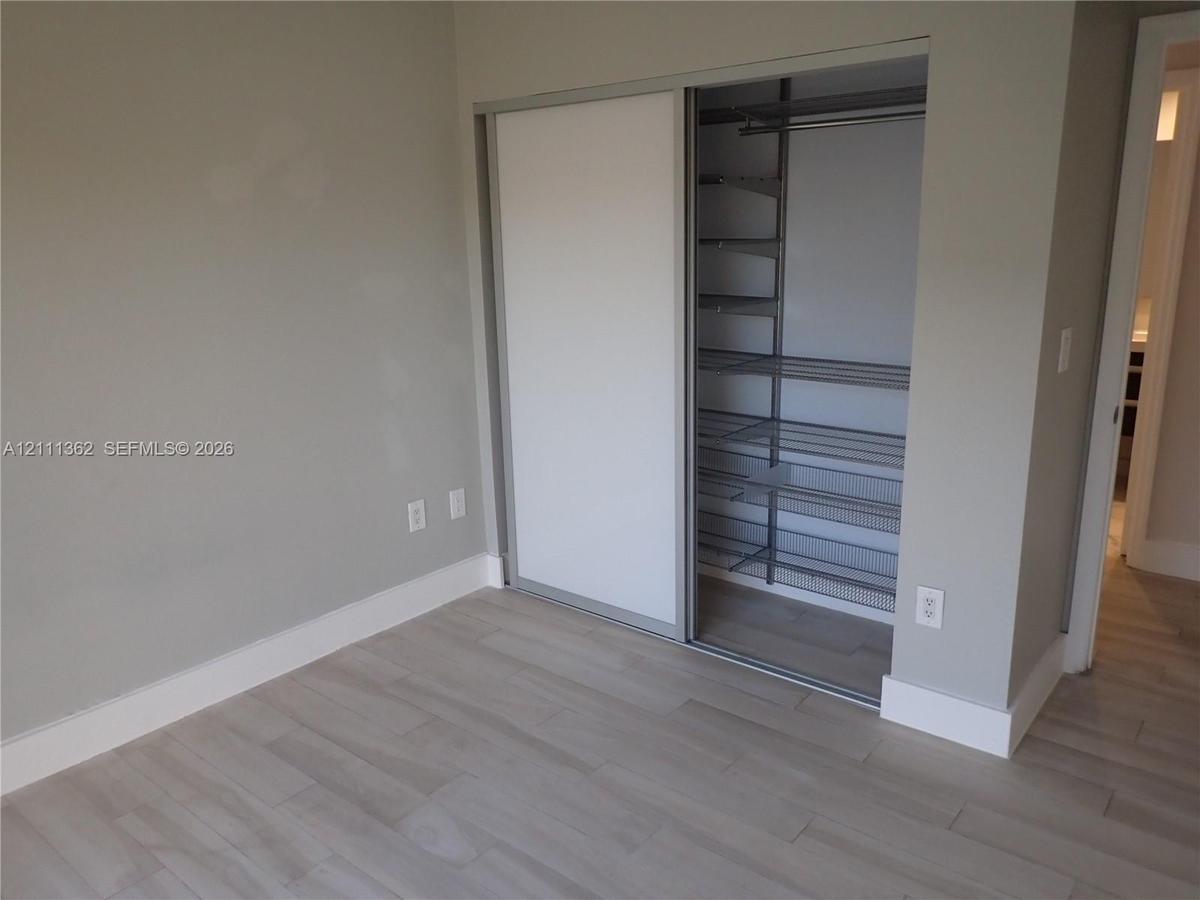 Closet with sliding doors and custom metal shelving, complemented by wood-finish flooring