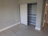 Closet with sliding doors and custom metal shelving, complemented by wood-finish flooring