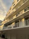 Multi-story building exterior featuring stacked private balconies with white railings, sliding glass doors, and ground-level garage access