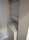 Stacked white laundry appliance unit situated within a recessed utility closet