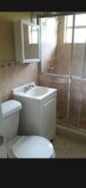Bathroom featuring a white vanity cabinet with an integrated sink, wall-mounted medicine cabinet, shower enclosure with sliding glass doors, and tiled