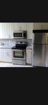 Kitchen featuring white Shaker-style cabinetry, stainless steel appliances, stone-surface countertops, and a stone backsplash