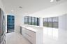 Modern kitchen featuring white flat-panel cabinetry, quartz countertops, a stainless steel dishwasher, stone-finish tile flooring, and floor-to-ceilin