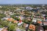 Aerial perspective featuring a flat-roof residence situated on a landscaped lot with mature palm trees and established perimeter vegetation
