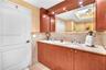Dual-sink vanity with stone countertop, wood cabinetry, stone tile backsplash, integrated oversized mirror, and recessed lighting