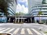 Modern high-rise exterior featuring glass-paneled balconies, floor-to-ceiling windows, a covered porte-cochère, and stone-paved motor court