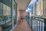 Covered balcony featuring patterned tile flooring, a wall-mounted light fixture, and a metal railing
