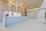 Large kitchen island with a white waterfall countertop, expansive wood-paneled wall with integrated linear lighting, stone-tiled backsplash, polished 