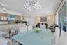 Open-concept living space featuring a tiered tile breakfast bar, glass-front cabinetry, a decorative crystal chandelier, and sliding glass doors