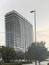 High-rise residential building featuring a glass facade, multiple levels of balconies with glass railings, and a tiered architectural design