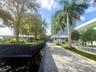 Paver walkway flanked by a water feature with textured cladding, palm tree-lined landscaping, and manicured green space
