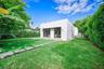 Minimalist exterior with smooth white stucco, dual sets of glass-paneled double doors, manicured turf lawn, and custom stone paver walkway