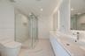 Bathroom featuring a dual-sink vanity with a solid-surface countertop, walk-in glass-enclosed shower with wall-mounted plumbing fixtures, recessed sho