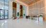 Grand lobby featuring polished white tile flooring, floor-to-ceiling glass entryway doors, geometric wood-paneled walls with integrated recessed light