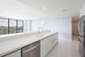 Kitchen featuring high-gloss white cabinetry, white stone countertops, stainless steel appliances, and large-format tile flooring