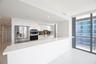 Modern kitchen featuring high-gloss white cabinetry, expansive stone countertop, stainless steel refrigerator, built-in wall oven, and floor-to-ceilin