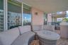 Covered balcony featuring floor-to-ceiling glass sliding doors, stone-tiled flooring, and metal railing