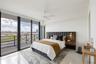 Primary suite with floor-to-ceiling windows, polished tile flooring, wall-mounted wooden bedside tables, integrated bedside lighting, and a white ceil