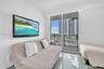 Sliding glass door opening to a private balcony with metal railing, reflective tile flooring, and wall-mounted television