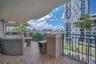 Covered balcony featuring tiled flooring, a solid concrete overhang, and dark metal railings with urban surroundings