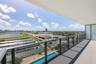 Covered balcony featuring a glass and metal railing, concrete flooring, and an expansive cityscape backdrop