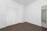 Room featuring wood-finish flooring, white walls, and a four-panel louvered closet door