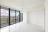 Primary suite with floor-to-ceiling sliding glass doors, white stone-finish flooring, white ceiling fan, and black-framed balcony railing