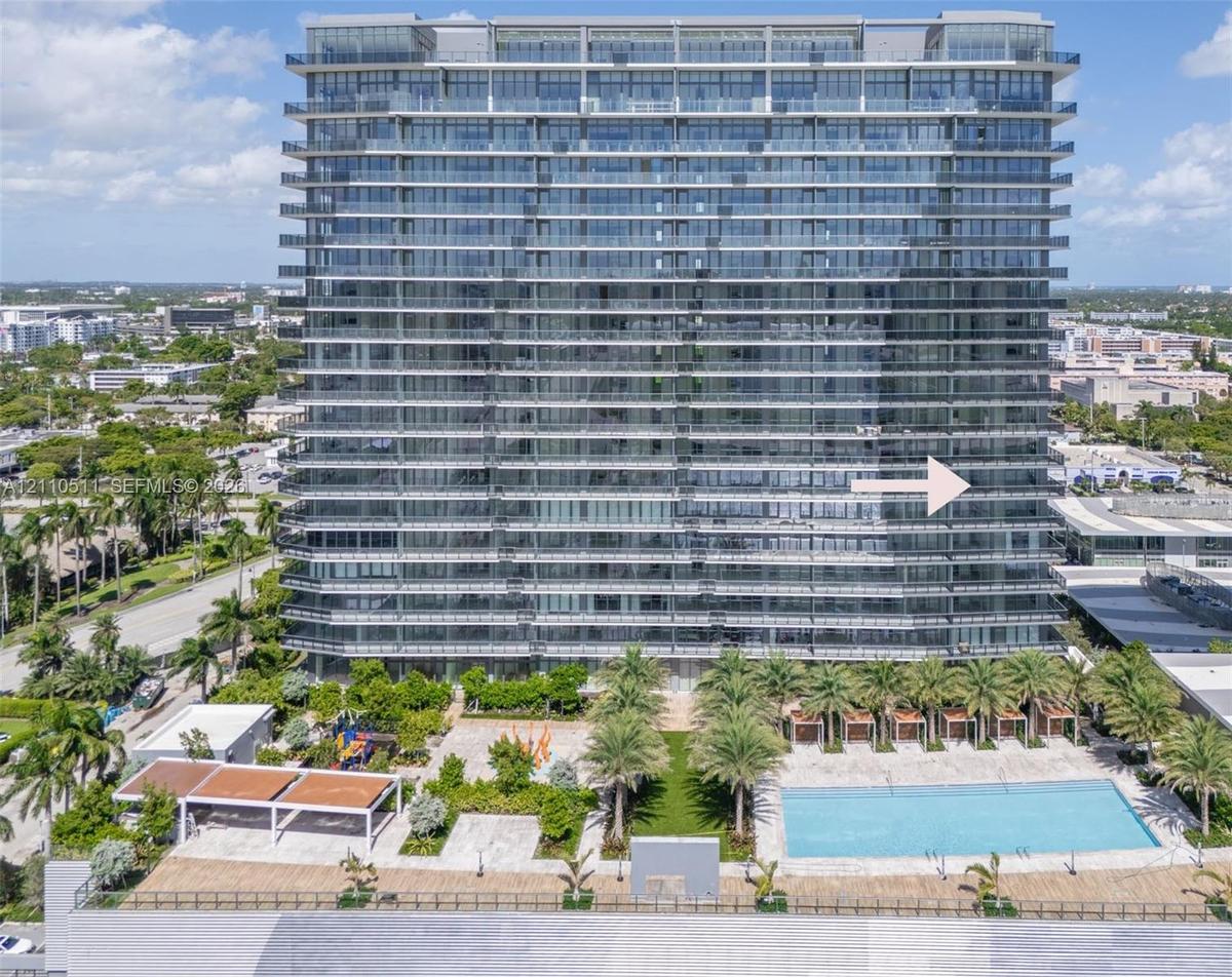 High-rise architectural exterior featuring glass-paneled balconies, a ground-level swimming pool, hardscaped patio, integrated landscaping, and covere