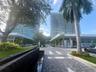 High-rise architectural exterior featuring glass curtain walls, multi-level structural design, stone-paver pedestrian walkways, decorative water featu