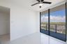Second bedroom, floor-to-ceiling windows, high-gloss stone-finish flooring, private balcony with metal railing, and integrated ceiling fan with lighti
