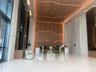 Lobby featuring high ceilings, large-format tile flooring, a geometric wood-paneled accent wall with integrated lighting, full-height stone cladding, 