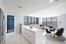 Modern kitchen featuring sleek white cabinetry, a spacious solid-surface island, floor-to-ceiling windows, and polished stone-finish flooring