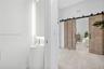Pedestal sink with a single-handle chrome faucet, LED-backlit mirror, large-format tile flooring, and wood-finish sliding barn doors with matte black 