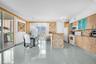 Open-concept area featuring light wood-finish cabinetry, tile-clad kitchen island, polished tile flooring, glass-paneled upper cabinets, and floor-to-