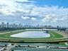 Panoramic perspective featuring a race track, central lake, and city skyline backdrop