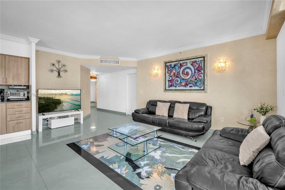 Large format tile flooring, crown molding, and wall-mounted decorative light fixtures