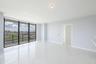 Open-concept interior featuring floor-to-ceiling glass windows, a private balcony with metal railing, and polished stone-finish tile flooring