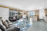 Open-concept living area featuring large-format tile flooring, floor-to-ceiling glass sliding doors, and a kitchen island with stone tile cladding