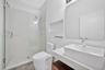 Bathroom featuring a vessel sink with a white stone-composite countertop, wood-finish vanity cabinet, walk-in shower with a glass enclosure and built-