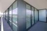 Wraparound balcony featuring floor-to-ceiling glass panels, dark metal framing, and a concrete-finish deck