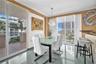 Dining area featuring polished tile flooring, floor-to-ceiling windows, a stone-accented breakfast bar, and a crystal chandelier
