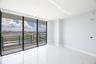 Floor-to-ceiling glass wall, private balcony with metal railing, high-gloss stone-finish flooring, and expansive urban scenery