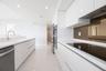 Modern kitchen featuring high-gloss white cabinetry, white stone countertops, integrated stainless steel appliances, a tinted glass backsplash, and po