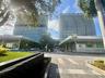 Modern high-rise towers featuring floor-to-ceiling glass facades, covered ground-level commercial spaces, paved stone driveways, and landscaped green 