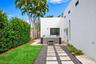 Outdoor space featuring a standalone spa, stone paver walkway with gravel surround, manicured lawn, and mature palm trees