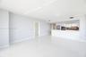 Open-concept interior featuring large-format tile flooring, white gloss cabinetry, a peninsula with a waterfall-edge countertop, and stainless steel b