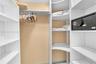 Walk-in closet featuring white floor-to-ceiling built-in shelving, adjustable storage cubbies, a hanging rod, and a built-in security safe