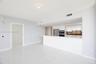 Open-concept area featuring white tile flooring with veining, white flat-panel cabinetry, a stone-surface peninsula, stainless steel appliances, and i